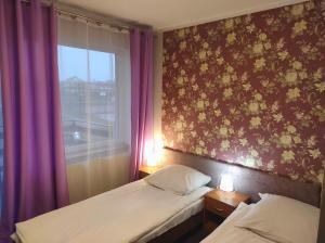 Pod Różą B&B في أوستكا: غرفة نوم بسريرين ونافذة ذات ستائر ارجوانية