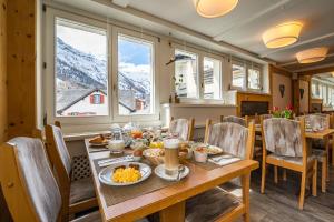 een eetkamer met een tafel met eten erop bij Hotel Christiania in Saas-Fee