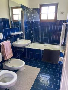a blue tiled bathroom with a toilet and a sink at from Geneva,Big House,7 bedrooms in Archamps