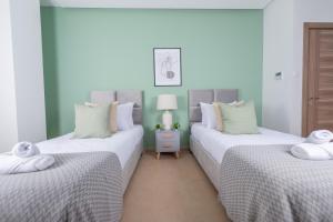 twee bedden in een kamer met wit en groen bij Radieux Appartement à Hydra in Hydra