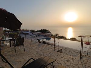 a patio with a table and chairs and the sunset at Point of View Andromeda in Drymon