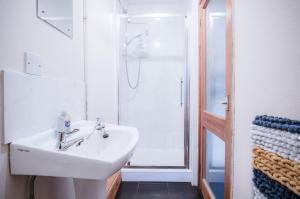 a bathroom with a white sink and a shower at Primrose - 1 Bedroom Cottage - Llanteg in Crunwear
