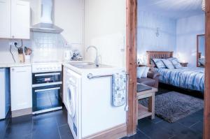 a kitchen with a sink and a kitchen with a bed at Primrose - 1 Bedroom Cottage - Llanteg in Crunwear