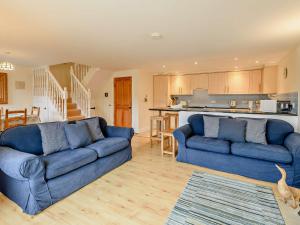 a living room with two blue couches and a kitchen at 3 Bed in Chideock DC087 in Chideock