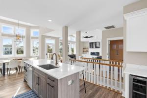 a kitchen and living room with white walls and wood floors at Coastal Charm Ocean Isle Beach custom beach home with 4 bedroom, 3 bath home with pool and elevator in Ocean Isle Beach