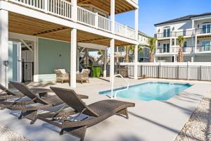 a patio with chairs and a swimming pool at Coastal Charm Ocean Isle Beach custom beach home with 4 bedroom, 3 bath home with pool and elevator in Ocean Isle Beach