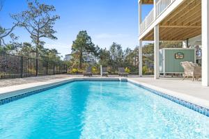 a swimming pool with blue water in a house at Coastal Charm Ocean Isle Beach custom beach home with 4 bedroom, 3 bath home with pool and elevator in Ocean Isle Beach