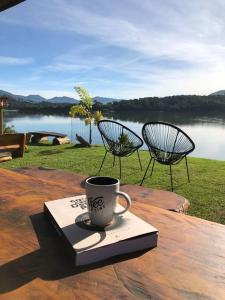 uma chávena de café sentada num livro sobre uma mesa em Lunar HOME (Casa Bolha) Pé na água em Joanópolis