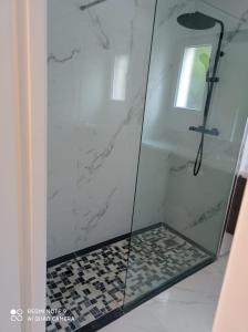 een douche met een glazen deur en een tegelvloer bij cosy appartement 6 pers grand jardin in Vitry-sur-Seine
