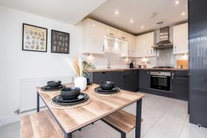 a kitchen with a wooden table with black cabinets at 6 Guests - 3 Bedrooms - Free WI-FI - Manchester in Manchester