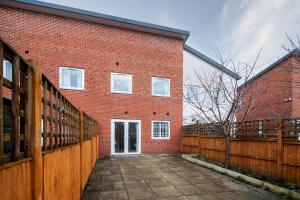 a red brick building with a wooden fence at 6 Guests - 3 Bedrooms - Free WI-FI - Manchester in Manchester