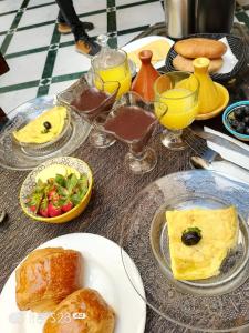 una mesa con platos de comida y vasos de zumo de naranja en Riad Deluxe, en Marrakech