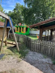 a playground behind a wooden fence with a slide at Mobilhome camping les petits écureuils 4 étoiles Biscarrosse in Biscarrosse