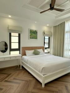 a white bedroom with a bed and a ceiling fan at Ako Villa Novaworld Phan Thiet in Bình Tú