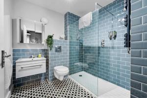 een blauwe betegelde badkamer met een toilet en een douche bij 2 bedroom apartment in the Town centre with free private parking in Cirencester