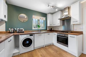 een keuken met witte kasten en een wasmachine en droger bij 2 bedroom apartment in the Town centre with free private parking in Cirencester