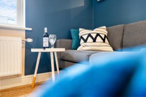 ein Wohnzimmer mit einem Sofa und einem Tisch mit einer Flasche Wein in der Unterkunft 2 bedroom apartment in the Town centre with free private parking in Cirencester