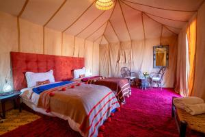 a bedroom with two beds in a tent at Erg Chegaga Desert Luxury Camp in El Gouera
