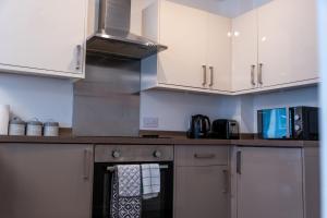 a kitchen with white cabinets and a stove top oven at Balvenie Apartment in Oban
