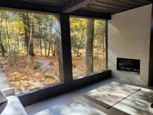 una sala de estar con una gran ventana con vistas al bosque en Black Pine Tree House en Acton