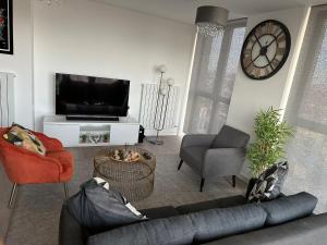 a living room with a couch and chairs and a clock at Immaculate 2-Bed Apartment in east London in London