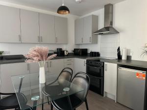 a kitchen with a glass table and black appliances at Immaculate 2-Bed Apartment in east London in London