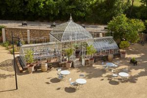 une serre avec des tables et des chaises dans un jardin dans l'établissement Château Les Carrasses, à Capestang