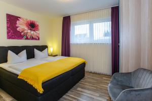 a bedroom with a bed and a chair and a window at Ferienapartments Pension Elsternest in Bad Liebenwerda