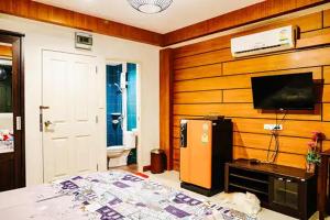 um quarto com uma cama e uma televisão de ecrã plano em Sleep Hotel em Chon Buri
