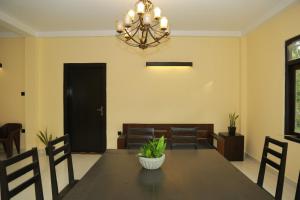 a dining room with a table and chairs and a chandelier at Charly breeze in Ahangama