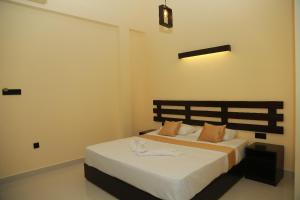 um quarto com uma cama com lençóis brancos e almofadas laranja em Charly breeze em Ahangama