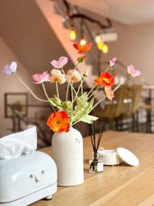 Willow Pillow Guest House & Poshtel في شومفون: مزهرية بيضاء مع الزهور على طاولة