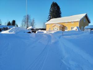 a snow covered road in front of a house at Ristijärven Pirtti Cottage Village in Ristijärvi