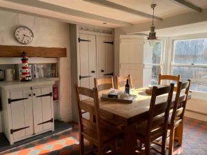 a kitchen with a table and chairs and a clock on the wall at Cilrhiw, Seaside Stone Cottage in Llangrannog in Llangrannog