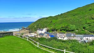 a town on a hill next to the ocean at Cilrhiw, Seaside Stone Cottage in Llangrannog in Llangrannog