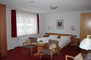 a hotel room with a bed and two chairs and a table at Gasthof Schwarzwaldtanne in Schönwald