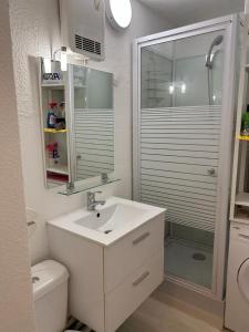 Un baño blanco con lavabo y ducha. en Studio meuble bord de mer, en Bormes-les-Mimosas