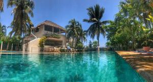 a swimming pool in front of a house with palm trees at Experiencia en la playa para 16 personas in Puerto Arista