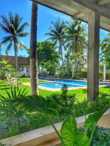 a resort pool with palm trees in the background at Experiencia en la playa para 16 personas in Puerto Arista