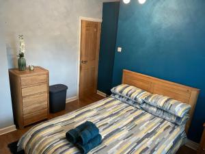 a bedroom with a bed with blue walls at Beautiful 3-Bed House in Romford in Romford