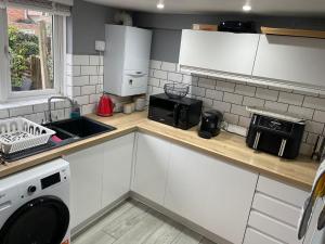 a kitchen with white cabinets and a sink and a microwave at Beautiful 3-Bed House in Romford in Romford