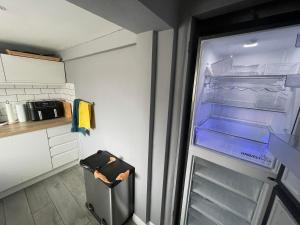 an empty refrigerator with its door open in a kitchen at Beautiful 3-Bed House in Romford in Romford