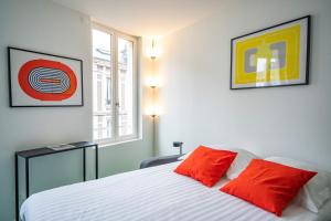 a bedroom with a bed with two red pillows at Studio - Alma in Le Havre