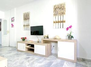 sala de estar con TV en una pared blanca en 2 bedrooms appartement with shared pool and wifi at Fuengirola en Fuengirola