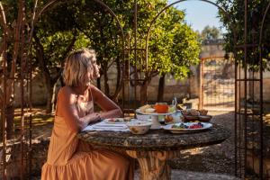 Una mujer sentada en una mesa con comida. en Masseria Brigantino, en Torre Canne