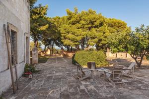 a stone pathway with benches and trees in the background at Masseria Brigantino in Torre Canne