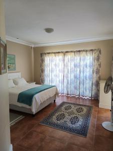 a bedroom with a bed and a window with a rug at Wave Echo in Plettenberg Bay