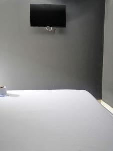 een slaapkamer met een wit bed en een flatscreen-tv bij HOTEL LA MATA 