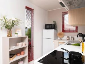 a kitchen with a sink and a white refrigerator at Camping maeva Respire de La Croze in Châtel-Guyon