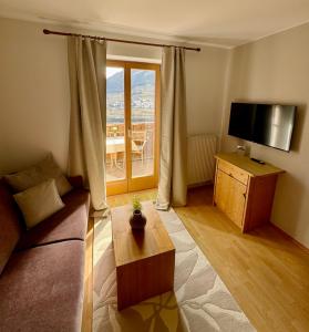 ein Wohnzimmer mit einem Sofa und einem TV in der Unterkunft Hotel Residence MaVie in Algund